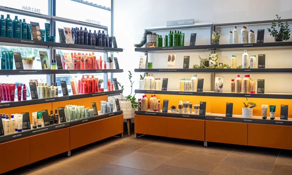 - Bella Capelli Sanctuario in Westlake, OH Shelves display various hair care products in bottles and tubes, organized by type, in a brightly lit store with large windows and potted plants. - Bella Capelli Sanctuario in Westlake, OH