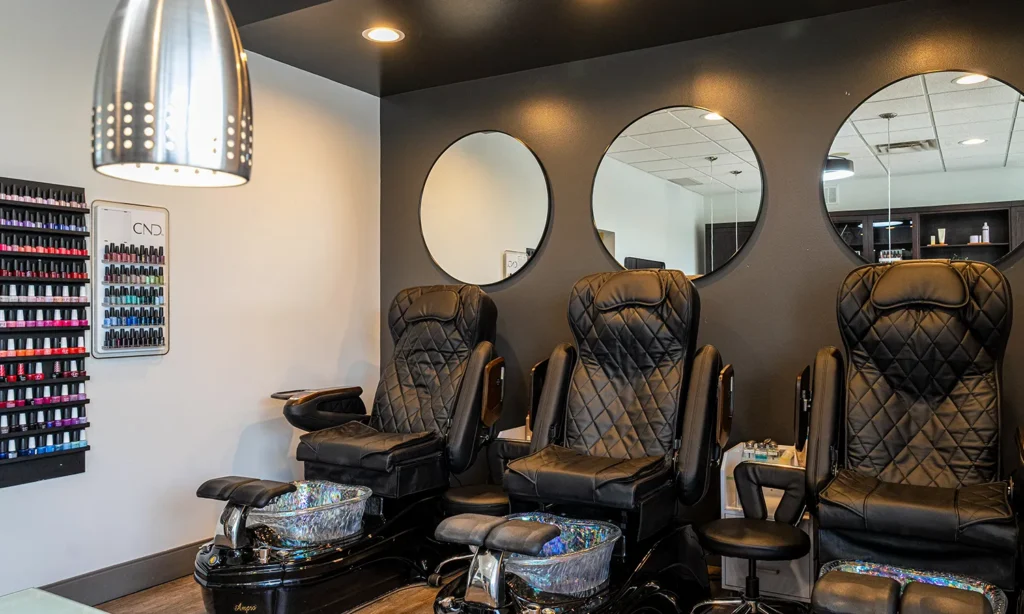 - Bella Capelli Sanctuario in Westlake, OH Three black pedicure chairs with foot baths are lined up against a gray wall with three round mirrors in a nail salon. A display rack of nail polish is mounted on the adjacent wall. - Bella Capelli Sanctuario in Westlake, OH
